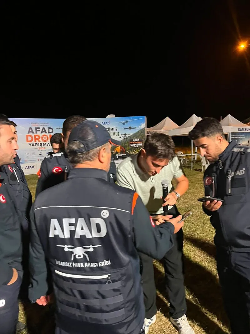 Gece yarışma alanında, AFAD insansız hava aracı ekibinden personel BosNets çalışanının etrafında toplanmış cihazı inceliyor.